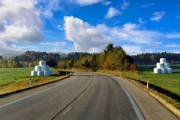 Beautiful European driving routes, highways and cars, with trees changing color in autumn, rural views in a fresh and clear morning with a cloudy blue sky.