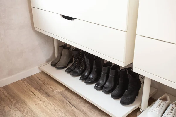 Organized shoe rack, shoe rack with black stylisch shoes and boots, on a wooden floor, besides a white wall. modern room — Stock Photo, Image