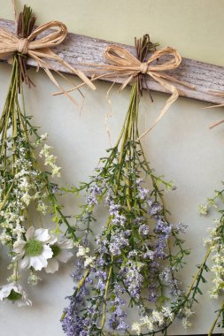 Ahşap arka planda ipte sallanan çeşitli parlak kurumuş çiçek demetleri, kurumuş çiçekleri ev dekorasyonu için modern hale getiriyor.