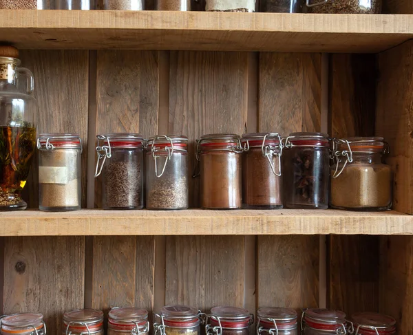 Garrafas com especiarias e temperos em rack de madeira. Várias ervas orgânicas diferentes para na cozinha olhar vintage — Fotografia de Stock