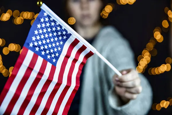 Young woman holding an American flag with sparkling light bokeh background, Usa Concept — Stock Photo, Image