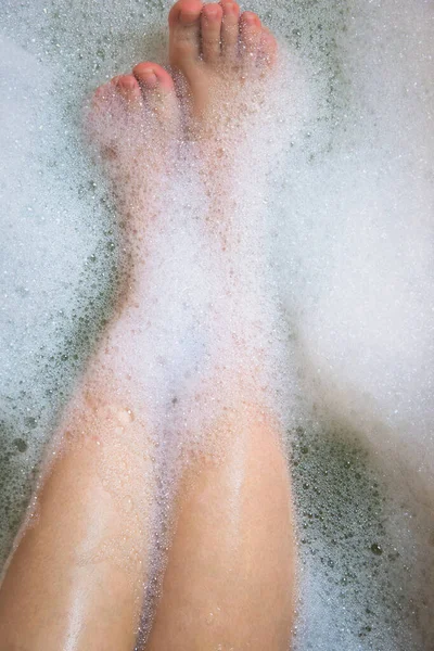 Vrouwen benen in de badkuip, baden met bubbelbad schuim bovenaanzicht, ontspanning schoonheid spa concept — Stockfoto