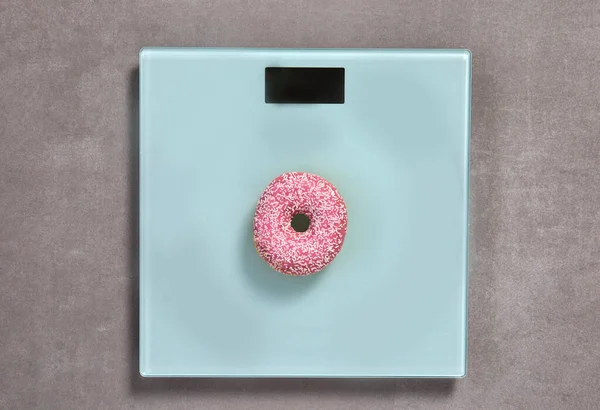 Вес шкалы со сладким розовым глазурованным пончиком с брызгами вид сверху, копия пространства для текста или дизайна, сахар, фасад концепции нездоровой пищи — стоковое фото