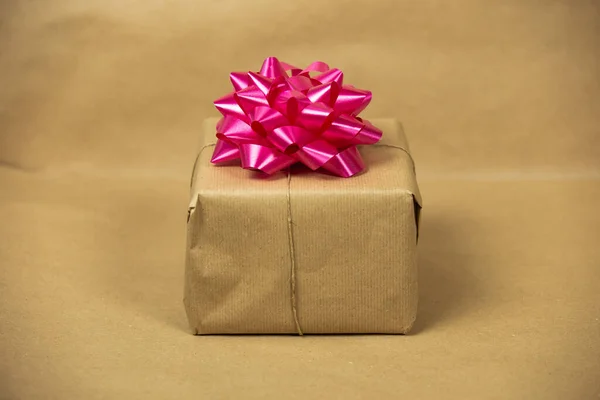 Brown plain paper gift box with pink wrapping decoration on brown background, present and birthday concept , retro design