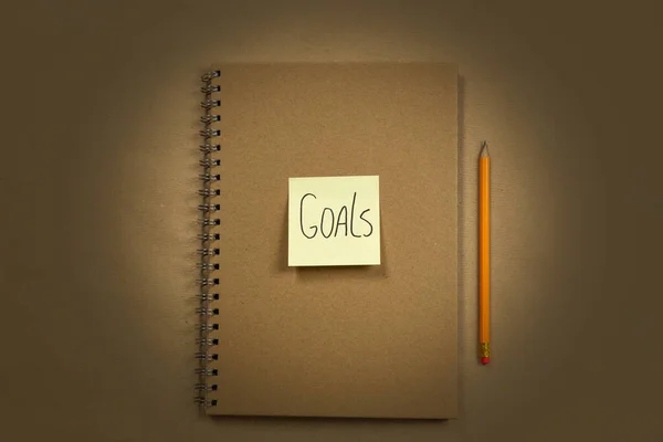 Cuaderno marrón con vista superior de nota adhesiva amarilla para Goal o para hacer bloc de notas de lista, textura de fondo marrón, espacio de copia, negocio o concepto de educación — Foto de Stock