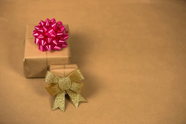 Две коробки в эко-коричневой простой бумаги с золотой и розовой обертывания украшения, подарок на день рождения, День матери День святого Валентина и другие стороны концепции на коричневом фоне — стоковое фото