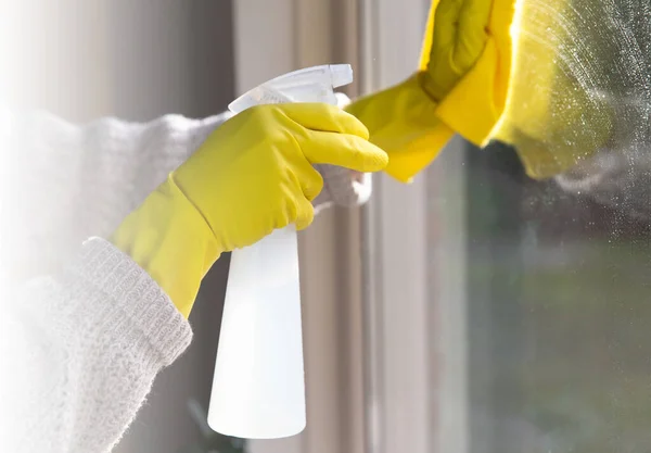 Limpieza de una ventana con detergente en aerosol, guantes de goma amarilla y paño de cocina en el concepto de superficie de trabajo para la higiene, el negocio y el concepto de salud —  Fotos de Stock