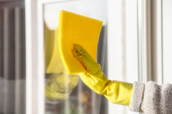 Hand in hand in gele rubberen handschoen met gele microvezel reinigingsdoek en spuitfles met sterilisatieoplossing maken reiniging en desinfectie voor een goede hygiëne, gezondheid en bedrijfsconcept — Stockfoto
