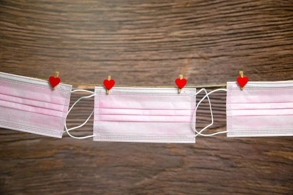 Różowa ochronna maska medyczna wisząca z kołki odzieżowe w kształcie serca izolowane na białym tle, Zdrowie, Covid-19 lub Walentynki koncepcja tła — Zdjęcie stockowe