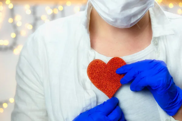 Healthcare worker holding red heart with blue medical gloves for epidemic coronavirus or other virus, health and love Valentine concept. human beauty