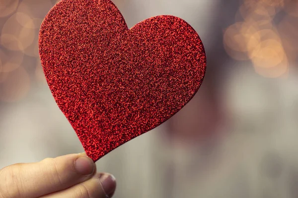 Kvinnliga händer håller gnistrande rött hjärta nära kroppen, ta hand, Hälsa, Alla hjärtans dag koncept romantisk design — Stockfoto
