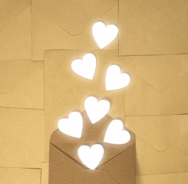 白い心、バレンタインデー、グリーティングカードのコンセプトトップビューの背景を持つクラフト茶色の紙の封筒、コピースペース — ストック写真