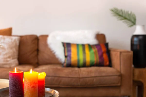 bright colorful interior living room with sofa on the background with burning candles blurred background, modern decoration style, copy space for lovely,cozy home interior concept stylish space for text