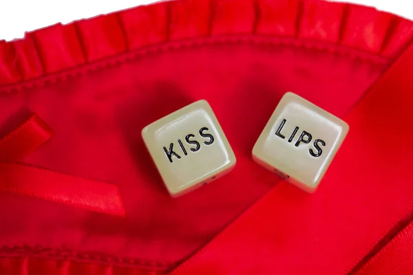 Two erotic dice for sexual game couple relation on red satin background texture isolated on white background top view with the text Kiss navel or lips — Stock Photo, Image