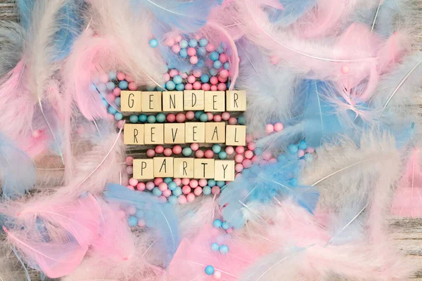 Gender reveal party written with wooden cubes surrounded with colorful bright pastel feathers for baby.boy,girl,party,greeting card or background concept top view. Copy space — Foto de Stock