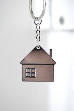 Beyaz kapıdaki gümüş ev anahtarı, küçük anahtarlık, yeni eve açılan kapı, ev, yatırım, gayrimenkul konsepti, metin kapatma alanı