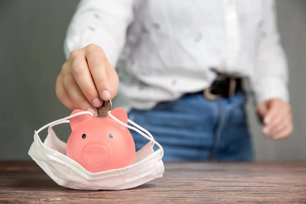 Einwerfen von Münzen in Sparschwein für Ersparnisse mit medizinischer Schutzmaske für Pandemie, Virus Covid-19, Coronavirus, Geschäft, fianancial, Sparkonzept mit Kopierplatz — Stockfoto