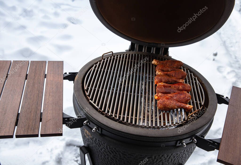 Winter bbq in the fresh white snow, Men grilling chicken wings in the winter onn grill close up