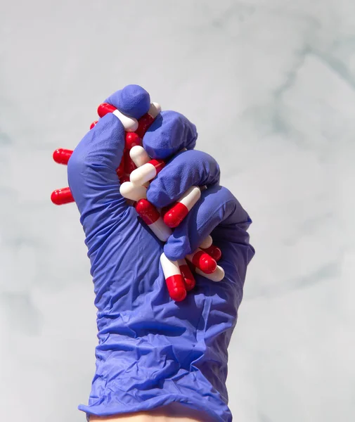Tangan dengan sarung tangan lateks biru meraih tangan penuh obat-obatan, Kapsul untuk Vitamin, obat-obatan, obat-obatan. Kesehatan, konsep bisnis — Stok Foto