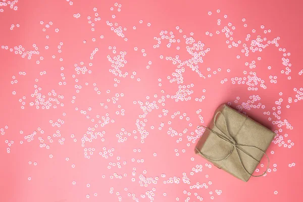 Caja de regalo con papel Kraft marrón rodeado de margaritas rosadas y fondo liso rosa, primavera, feliz día de las madres, San Valentín y otra vista superior concepto Holliday, diseño moderno — Foto de Stock