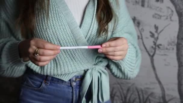 Pozitif hamilelik testi tutan güzel, şaşırmış genç bir kadının portresi. Hamilelik testi uygulayan genç bir kadın. — Stok video