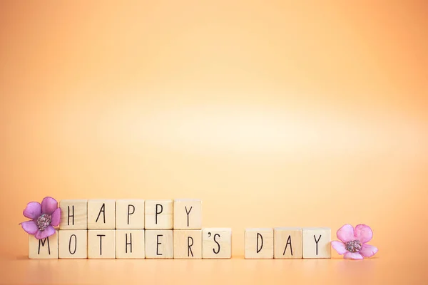 Happy Mother\'s Day Card. Text Happy mothers Day on bright pastel orange colored background with colorful purple flowers, modern retro design with copy space, Mother,Spring,Greeting card,Holiday concept space for text