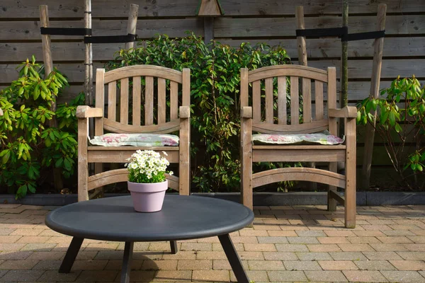 Cozy seating area in the garden of a modern home in the spring, wooden seats with colorful flowers in flower pot. backyard design on a sunny day — Stock Photo, Image