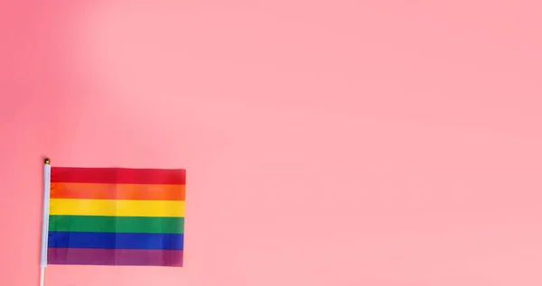 Bandeira do arco-íris LGBT, bandeira do orgulho no fundo rosa vista superior com espaço de cópia, de pé para pessoas gays direitos humanos, design moderno retro — Fotografia de Stock