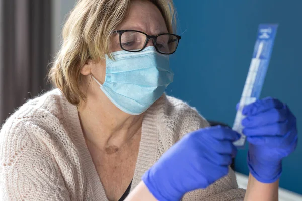 Mujer mayor estudiando y haciéndose la autoprueba para Covid-19, kit de prueba casera para coronavirus — Foto de Stock