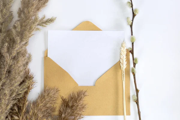 Mockup cartão minimalista com flor de junco, envelope de artesanato, flor, flat lay, vista superior Cartão de papel branco em branco e envelope para espaço de cópia — Fotografia de Stock