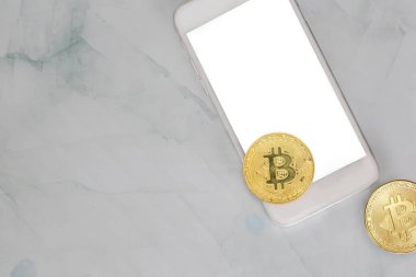 Altın Bitcoin, mermer arka plandaki akıllı bir telefonda fotokopi alanı, kripto para birimi ya da dijital para konsepti, siyah cep telefonu modern tasarımı ile yatar.