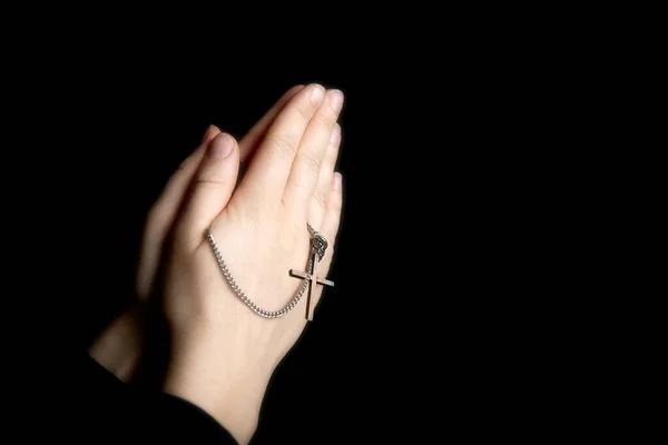 Praying hands holding a rosary, Closeup holding necklace with cross,pray for god in the dark, religious Christian symbol