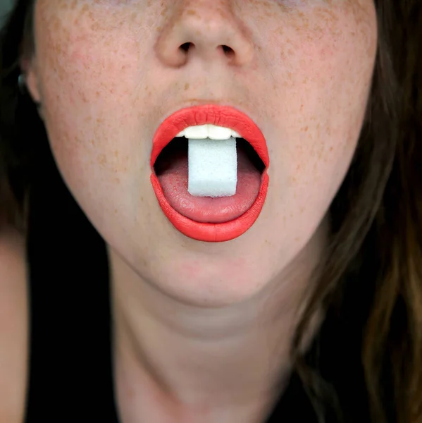 Close up of a woman with a sugar cube on her tongue in her mouth, unhealthy food,candy,sweets concept — Stock Photo, Image