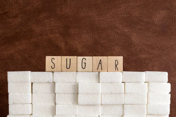 Сахар кубики стены с текстом Сахар на коричневом природном фоне текстуры, здоровье, диабет, медицинский, сахар, sweet.junk концепции питания — стоковое фото