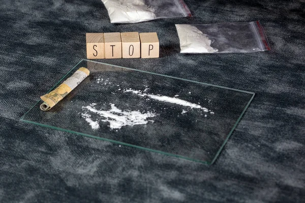 Drugsverslaving, witte poederlijn, cocaïne, speed of andere drugs en spuit met heroïne en de tekst STOP. Onzin, Verslaving, Drugsconcept achtergrond — Stockfoto