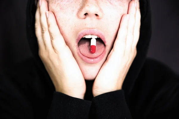 Женщина держит таблетку, капсулу с наркотиком на языке, подростка, принимающего xtc.cocaine или другие препараты или лекарства — стоковое фото