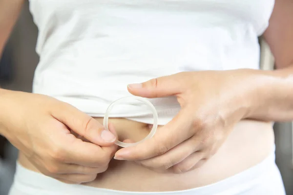 Controle de natalidade, hormônio, anel de contracepção em uma mão feminina roupa interior branca e barriga, anel vaginal para uso contraceptivo com espaço de cópia — Fotografia de Stock
