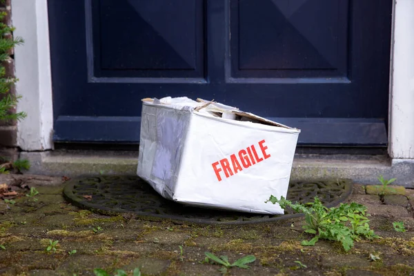 Caja de cartón de entrega dañada en la puerta principal de una casa, paquete frágil con abolladuras, mal concepto de entrega —  Fotos de Stock