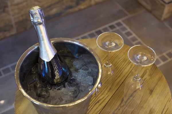 Bouteille de champagne dans une glacière, seau avec glace et deux verres de champagne sur une table en bois. dîner romantique et concept de fête — Photo