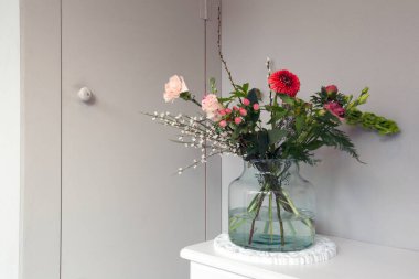 Güzel bahar çiçekleri cam bir vazo, gri duvarın yanında şık bir ev, modern iç dekorasyon kopya alanı beyaz masa