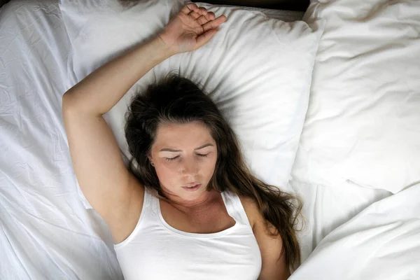 Young girl with freckles sleeping with white sheets top view, Portrait of the beautiful young woman sleeping in white bed in clean bedroom, lying down closeup