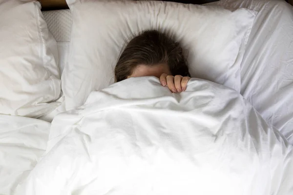 Young girl with freckles sleeping with white sheets top view, Portrait of the beautiful young woman sleeping in white bed in clean bedroom, lying down closeup