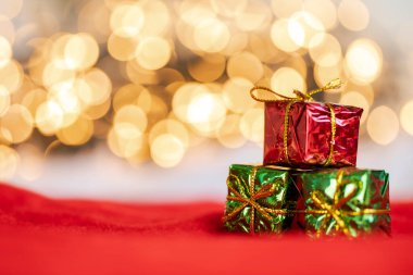 Bokeh ışıklarına karşı kırmızı ve gümüş takılar mevcut. Fotokopi alanı ve metin için alanı olan altın rengi parlak arkaplan.