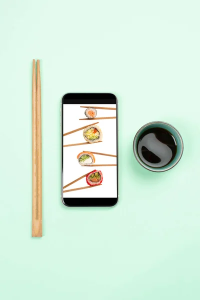 Online food delivery concept, sushi on phone\'s screen and chopsticks