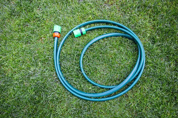 Reel of hose pipe and spraying head on grass. Flat lay. — Stock Photo, Image