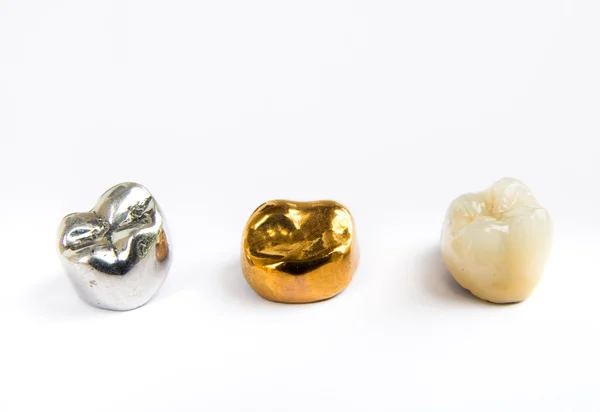Зубная керамика, золото и металлические зубные коронки на белом фоне. Isolated . — стоковое фото