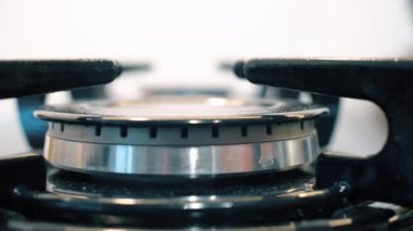 Gas is switching on, apearing blue flame. Gas stove on black background. Close up of blue gas fire is ignited on the hob.
