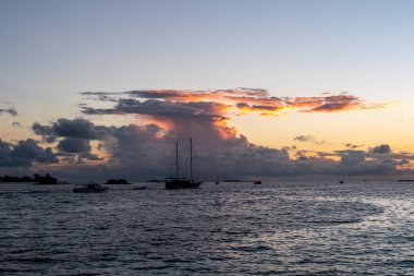 Tahta gemi kümülonimbus fırtına bulutları ve arka planda günbatımı ile hareket ediyor, Maldivler.