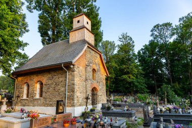 Milowka, Polonya, 08.07.2021. Mezarlıktaki Aziz Mary Magdalene 'e adanmış tarihi yenilenmiş tuğla şapel. Etrafında geleneksel dekore edilmiş granit mezarlarla..