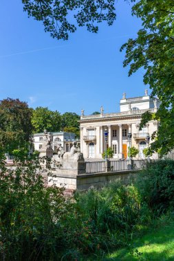Varşova, Polonya, 15.08.20. Varşova Kraliyet Hamamları Parkı 'nda, göl kenarındaki klasik hamam sarayında bulunan ve yemyeşil bitki örtüsünün içinden görünen saray (Lehçe: Palac Na Wyspie)..